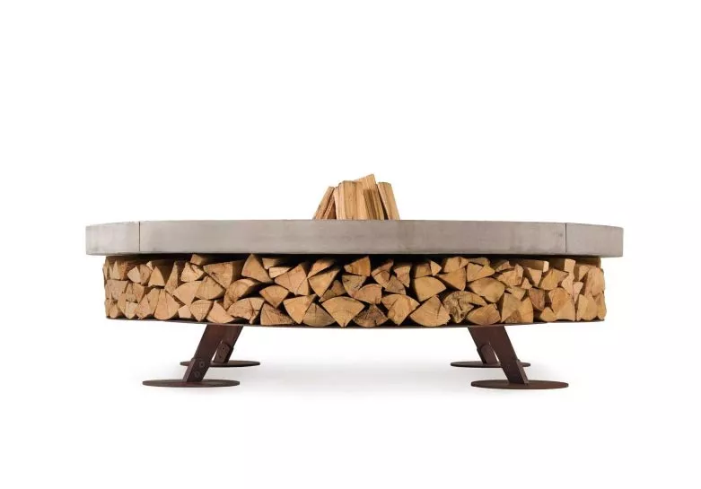 AK47 Ercole Small Stahl Feuerstelle 150 cm Beton Braun ohne Hintergrund mit Holzstapeln darunter