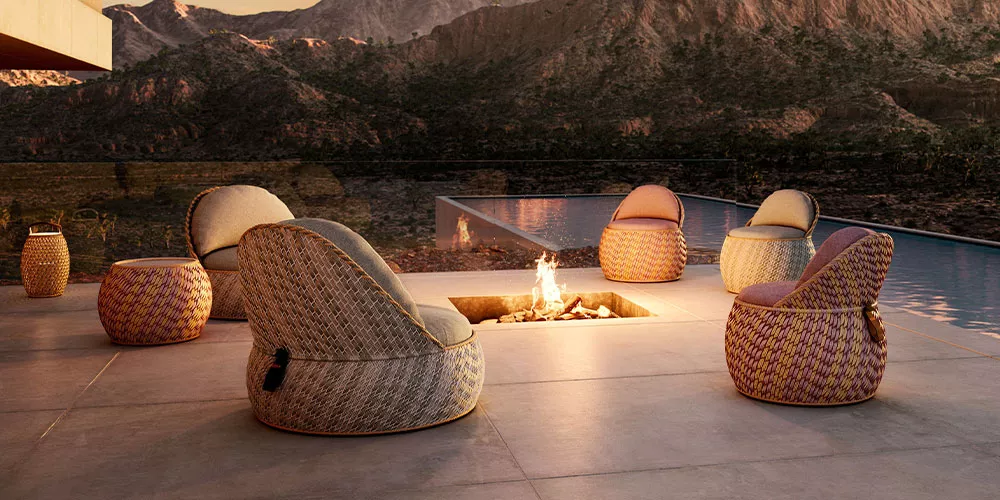 Dedon Kollektion Dala zeigt gemütliche Outdoor-Sitzmöbel um eine Feuerstelle auf einer Terrasse mit Bergblick im Hintergrund
