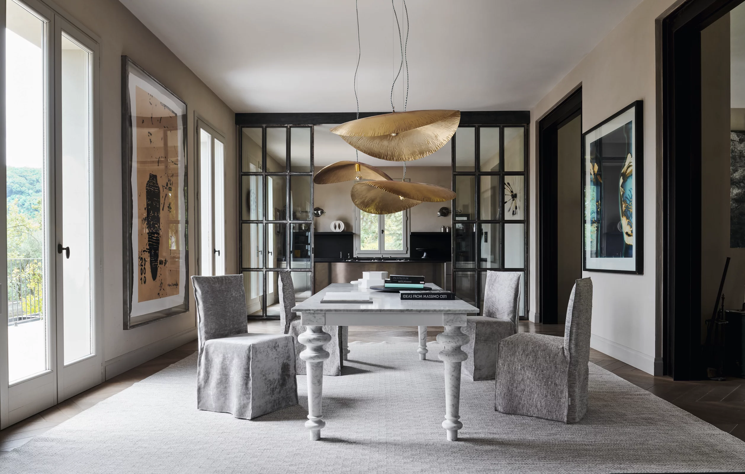 Ein elegantes Esszimmer mit grauen Loll Next Nuvola Stühlen und einem weißen Tisch auf einem hellen Teppich, umgeben von großen Fenstern.