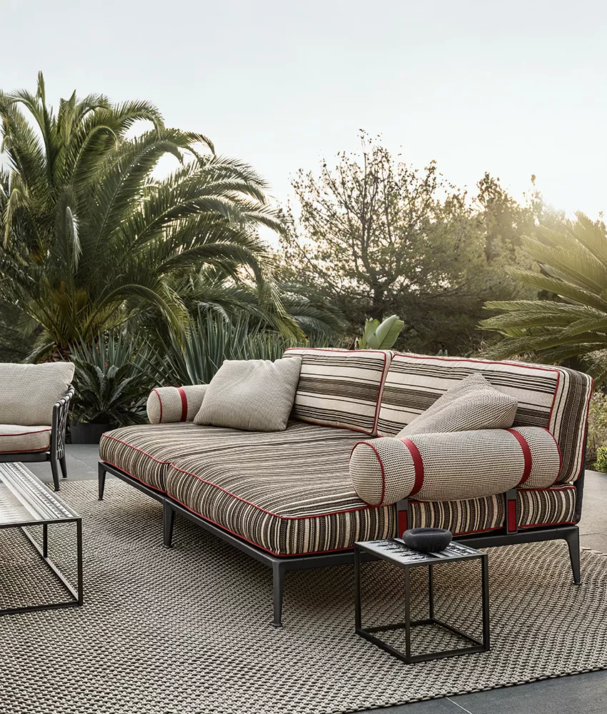 B&B Italia Ribes Outdoor Lounge in gestreiftem Design auf einer Terrasse mit Palmen im Hintergrund und einem Beistelltisch daneben