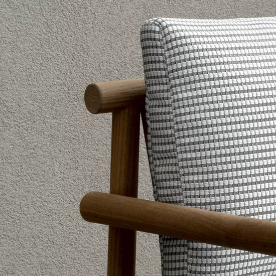 B&B Italia Ayana Stuhl mit Armlehnen in Nahaufnahme zeigt die Textur des Polsters und die Holzstruktur der Armlehnen vor einer neutralen Wand.