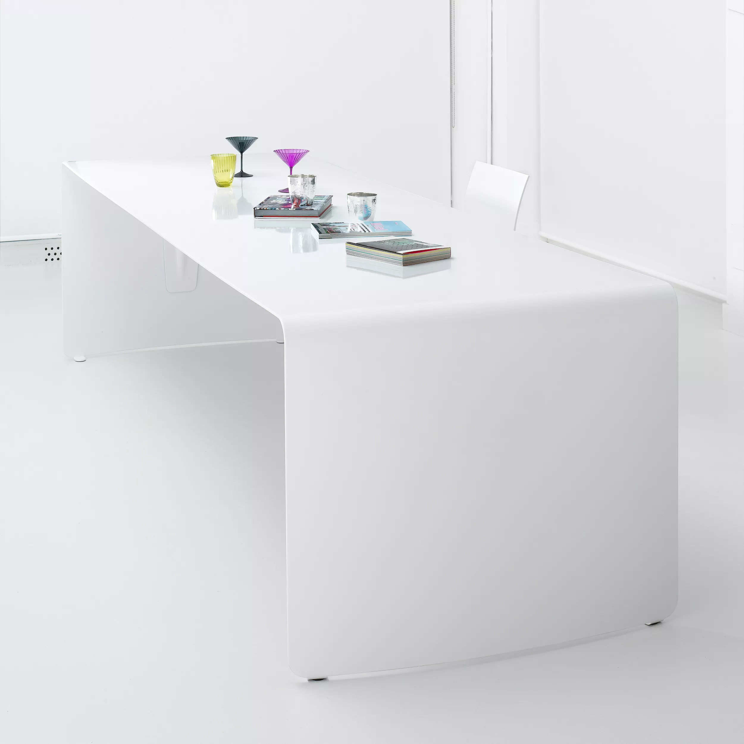 MDF Italia La Grande Table Tisch in Weiß mit Büchern und Gläsern darauf in einem minimalistischen Raum ohne Hintergrund