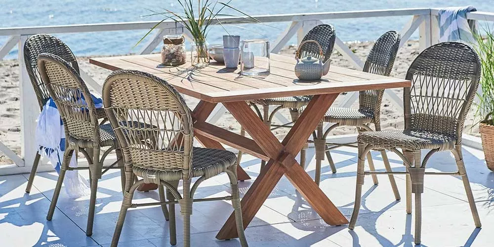 Essgruppe von Sika-Design aus Rattan und Holz in Naturtönen, bestehend aus einem Tisch und sechs Stühlen, auf einer Terrasse am Meer.