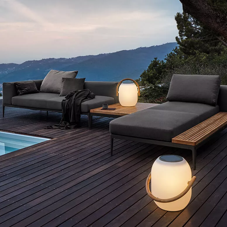 Gartenmöbel-Set Grid von Gloster in Anthrazit auf Holzterrasse mit Bergblick bei Sonnenuntergang, bestehend aus Sofa und Liege.