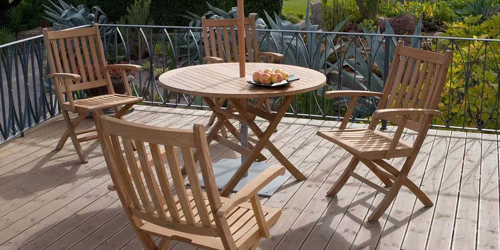 Barlow Tyrie Ascot Essgruppe aus Teakholz auf einer Terrasse mit Holzboden, bestehend aus einem runden Tisch und vier Stühlen.