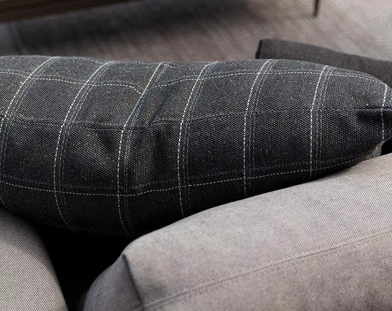 Schwarzes Grid-Polster von Villa Schmidt mit weißem Karomuster auf grauem Sofa in Nahaufnahme.