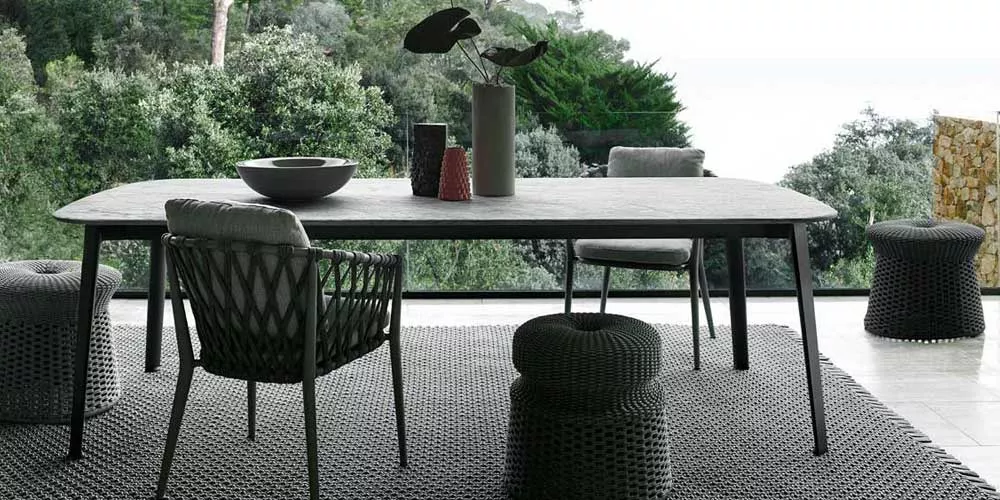 Essgruppe von B&B Italia mit dem Namen Ginepro in einem modernen Esszimmer mit Blick auf einen grünen Garten und stilvollen Dekorationen.