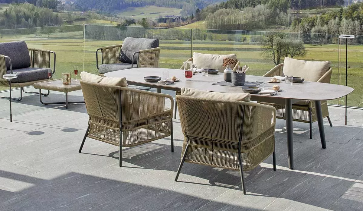 Varaschin Ellisse Essgruppe in Beige auf einer Terrasse mit Panoramablick, bestehend aus Tisch und Stühlen, ideal für den Garten.