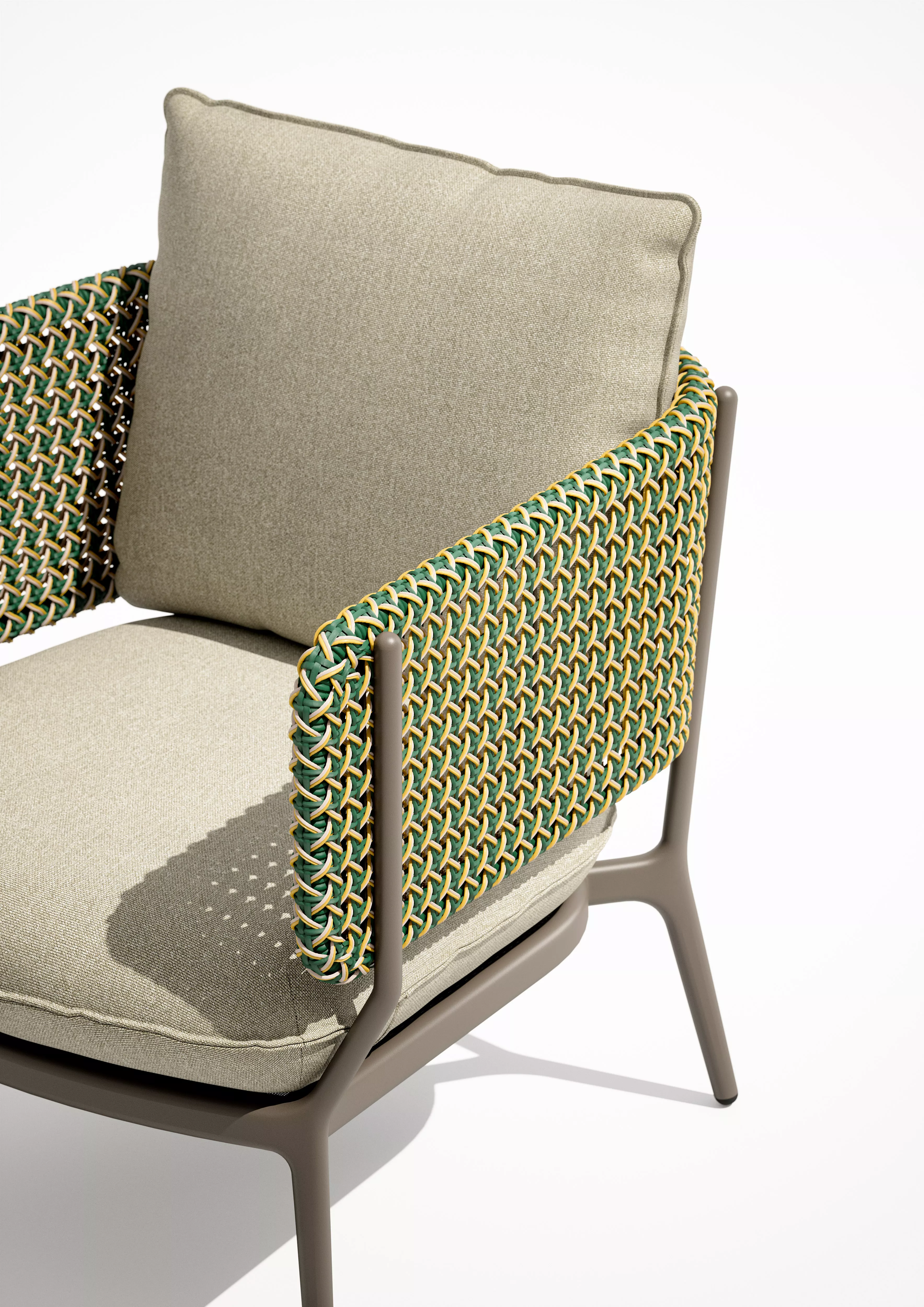 DEDON BELLMONDE Sessel in Nahaufnahme mit grünem und beigem Geflecht und beigen Kissen ohne Hintergrund