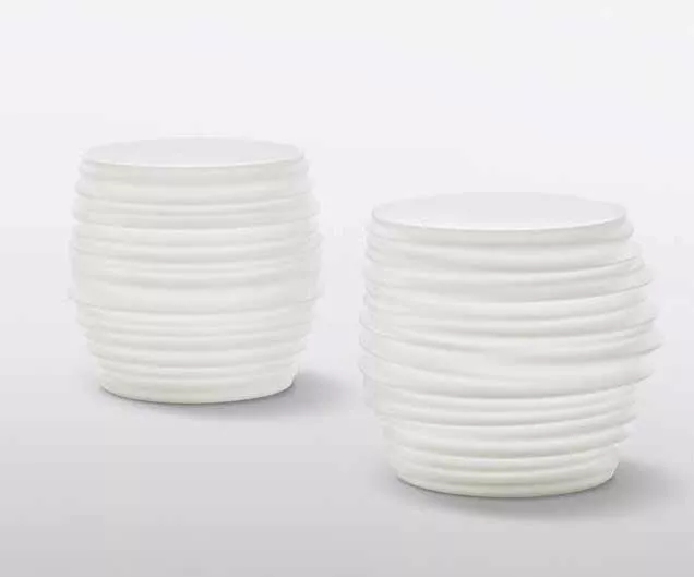 Zwei weiße Dedon Babylon Hocker Beistelltische mit geriffelter Oberfläche auf weißem Hintergrund.