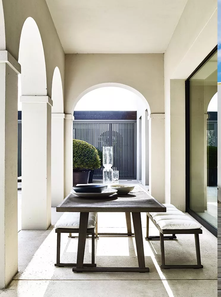 B&B Italia Gio Gartentisch 220 cm auf einer überdachten Terrasse mit weißen Bögen und modernen Gartenmöbeln in einer eleganten Umgebung.