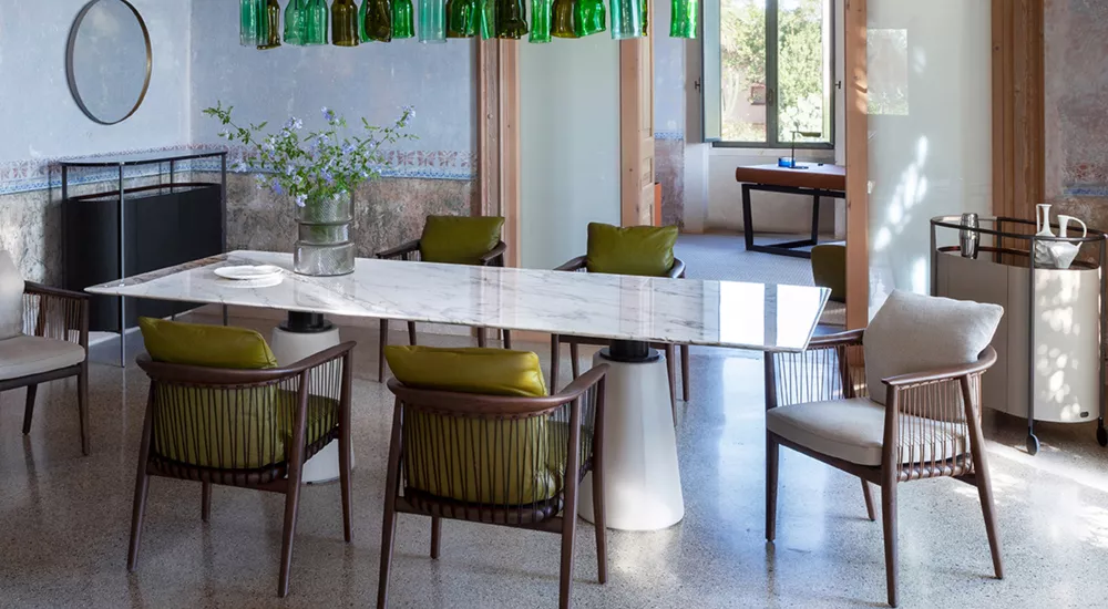 Esszimmer mit Poltrona Frau Viola Stühlen in Grün, um einen weißen Marmortisch, in einem lichtdurchfluteten Raum mit Glasflaschenleuchte.
