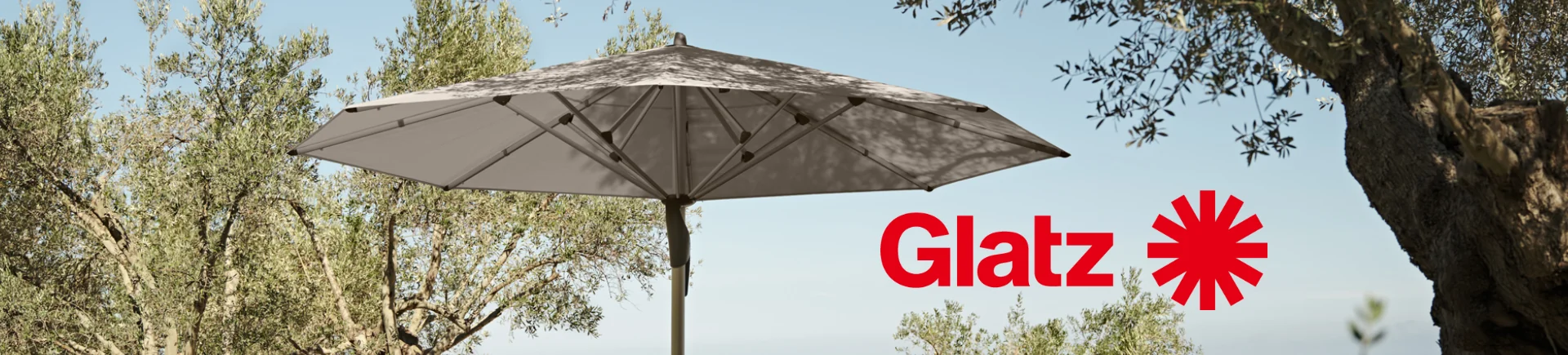 Glatz Sonnenschirm in Beige vor einem Hintergrund aus Bäumen und blauem Himmel, stimmungsvolles Outdoor-Bild.