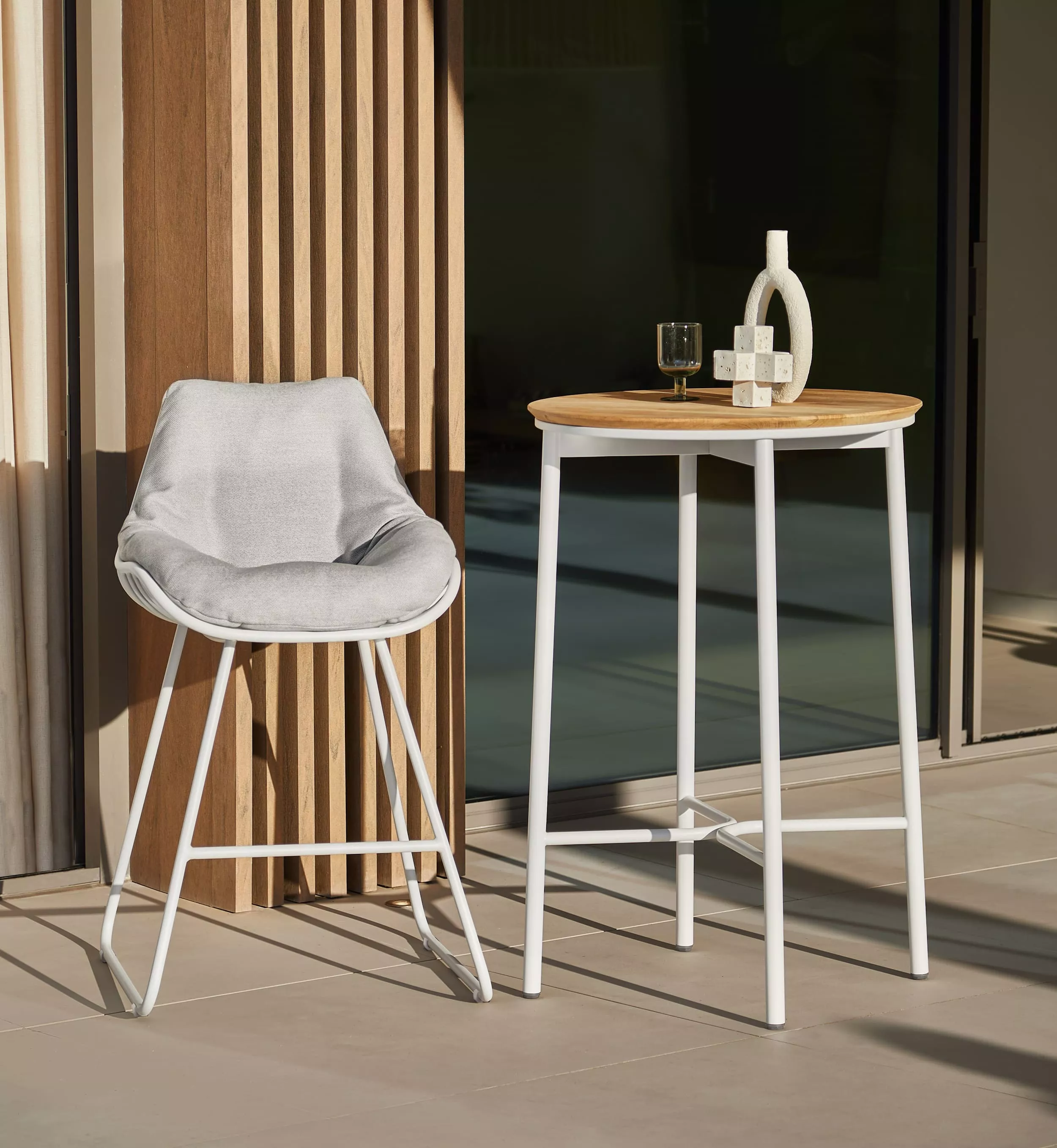 Solpuri Chill-A Barhocker und Bartisch in modernem Design auf einer Terrasse mit Getränken und Dekoration im Sonnenlicht