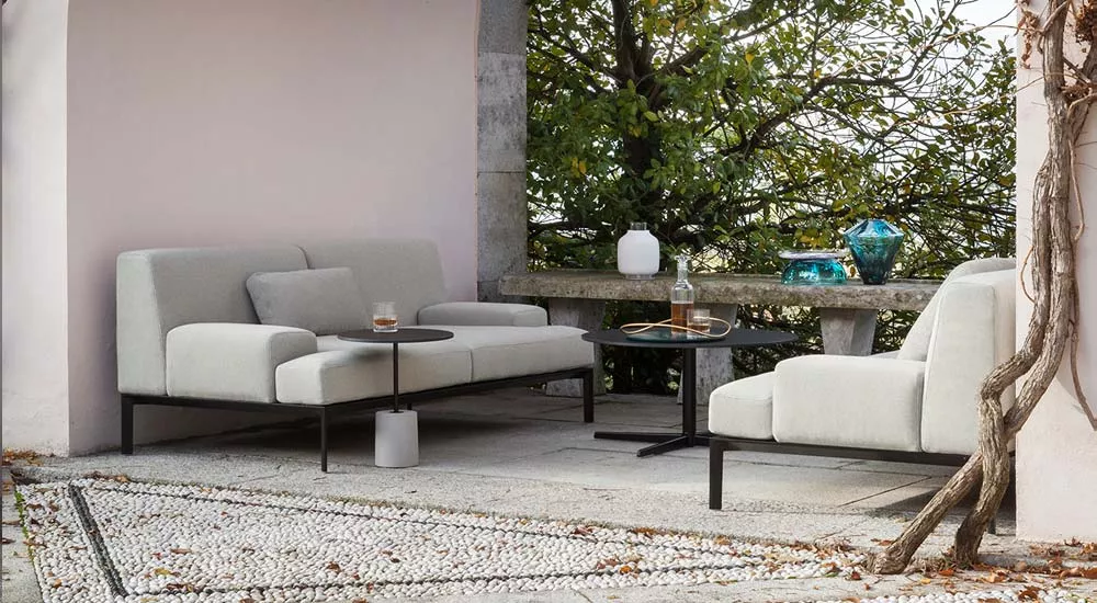 Lapalma ADD-SOFT Outdoor-Loungegruppe in hellem Grau auf einer Terrasse mit Steinboden und grüner Hintergrundbepflanzung.