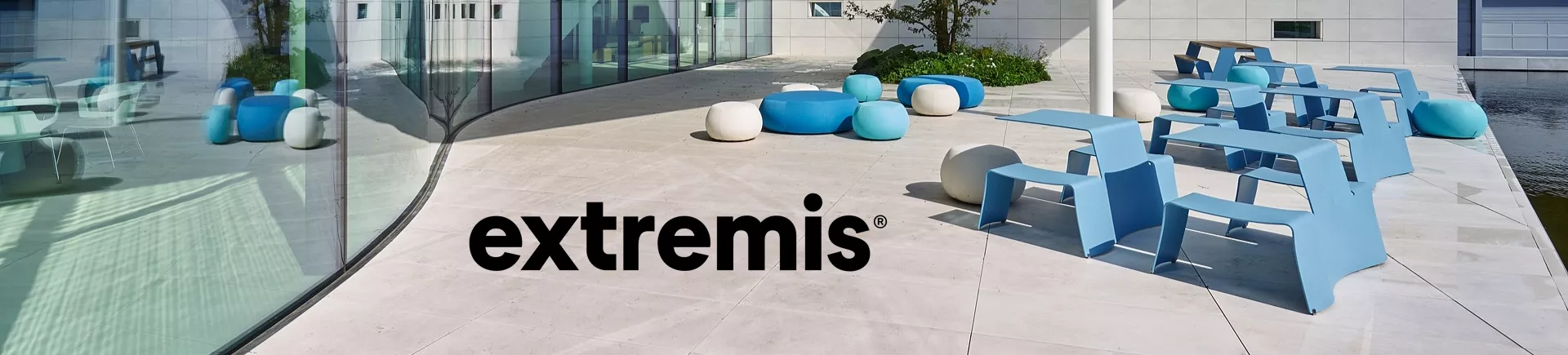 Moderne Terrasse mit extremis Möbeln in Blau und Weiß vor einem Gebäude mit Glasfassade, sonnige Stimmung, klare Linien.