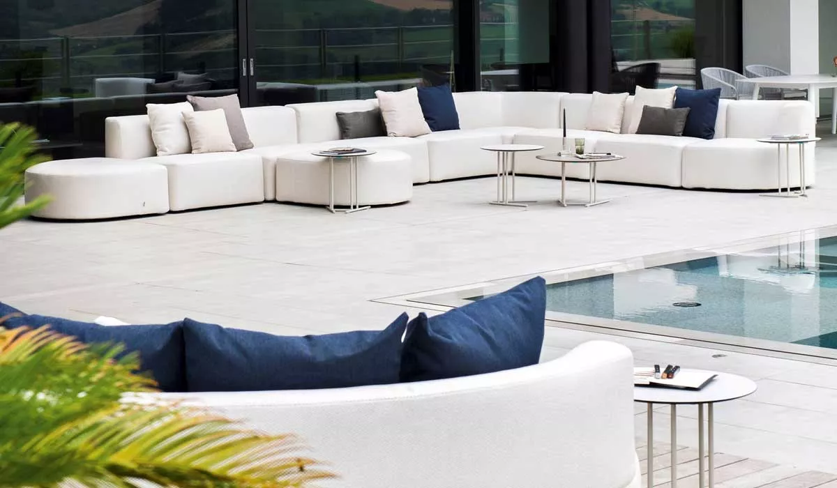 Varaschin Loungegruppen Gartenmöbel in Weiß auf einer Terrasse mit Pool, umgeben von Pflanzen und mit Blick auf die Landschaft.