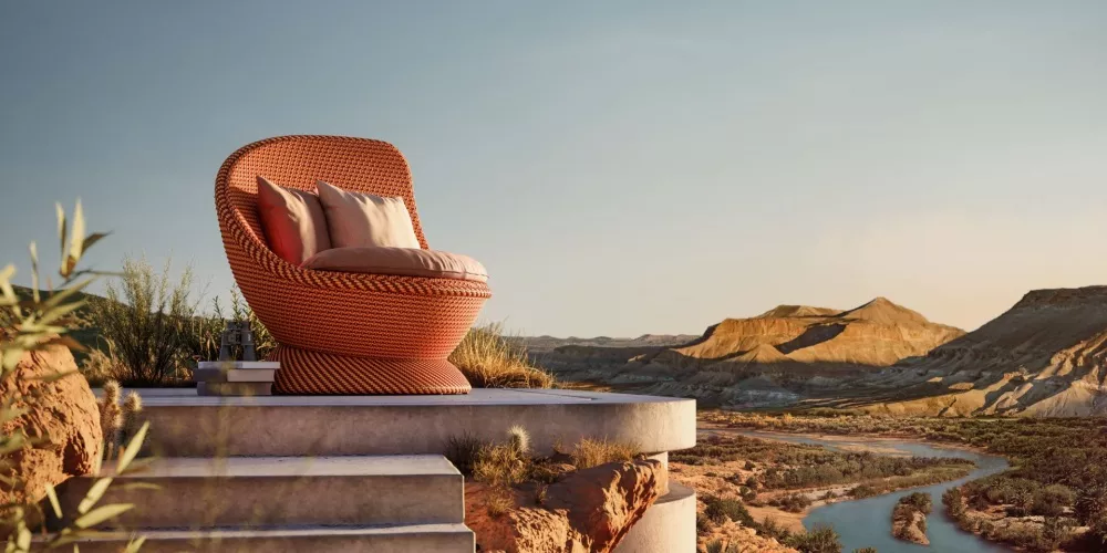 Dedon Mysterious Desert Papyon Sessel steht auf einer Terrasse mit Blick auf eine Wüstenlandschaft mit Fluss und Bergen im Hintergrund
