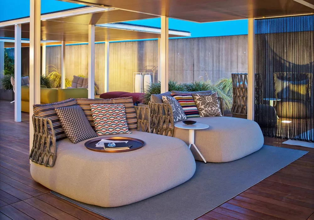 B&B Italia Fat Outdoor Loungegruppe mit beigen Gartensofas und bunten Kissen auf einer Terrasse bei Abenddämmerung