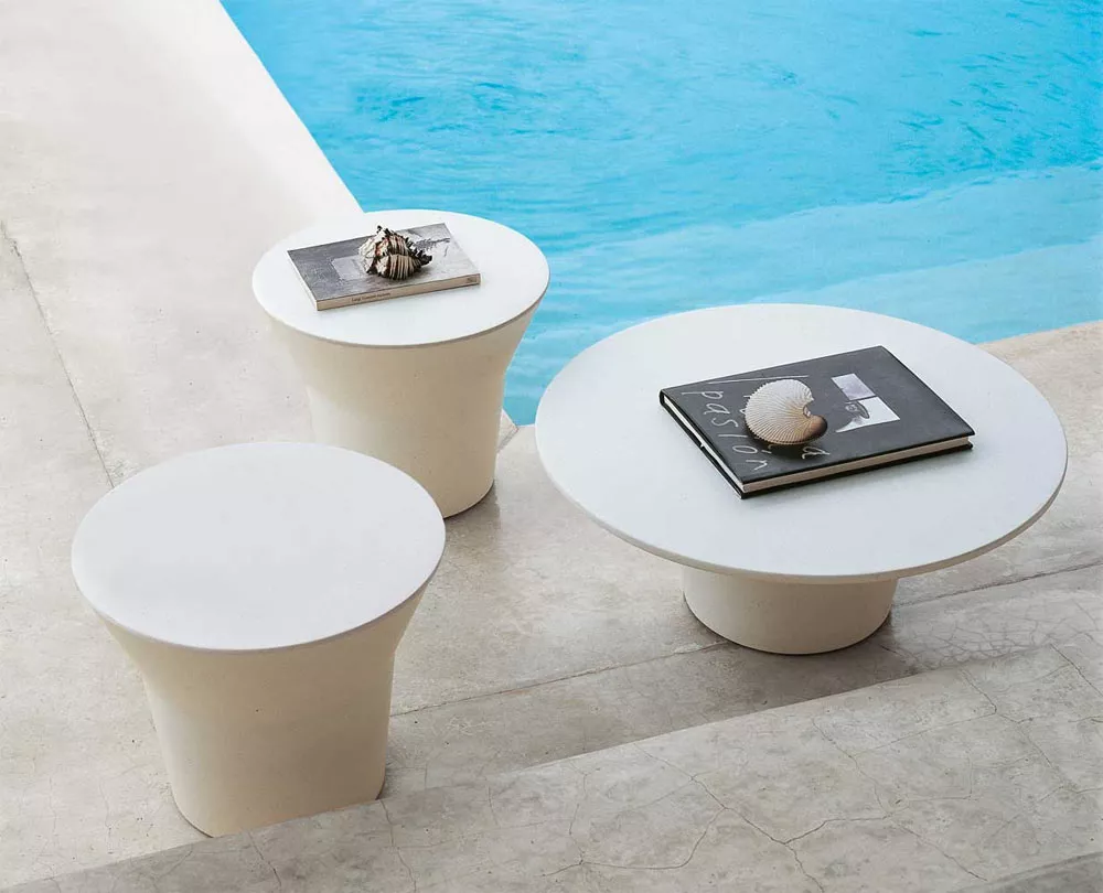 Drei B&B Italia Springtime Outdoor Beistelltische in Weiß neben einem Pool mit Büchern und Muscheln darauf