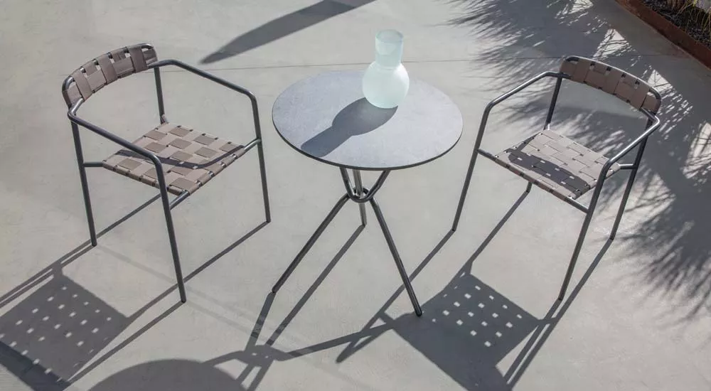 Fischer Möbel Tonic Essgruppe in Grau mit zwei Stühlen und rundem Tisch auf einer Terrasse bei Sonnenlicht.