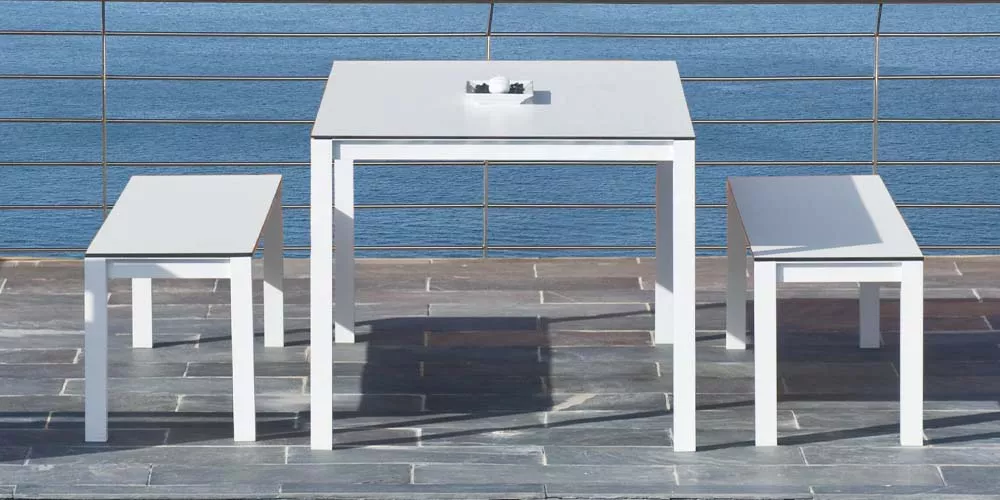 Calma Una weißer Tisch und Bänke auf einer Terrasse mit Meerblick, quadratisch, modernes Design, technische Ansicht.