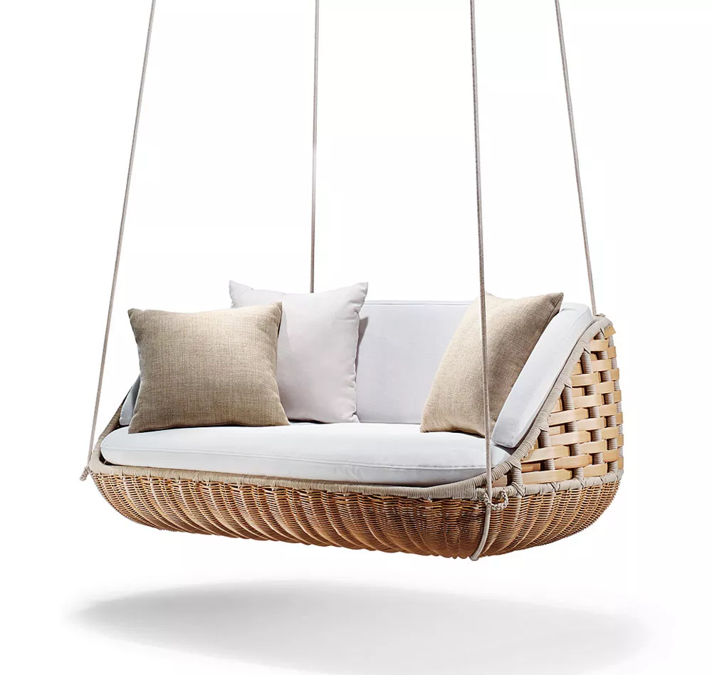 Dedon Swingus 2er Sofa in hellem Rattan mit weißen und beigen Kissen schwebend vor weißem Hintergrund