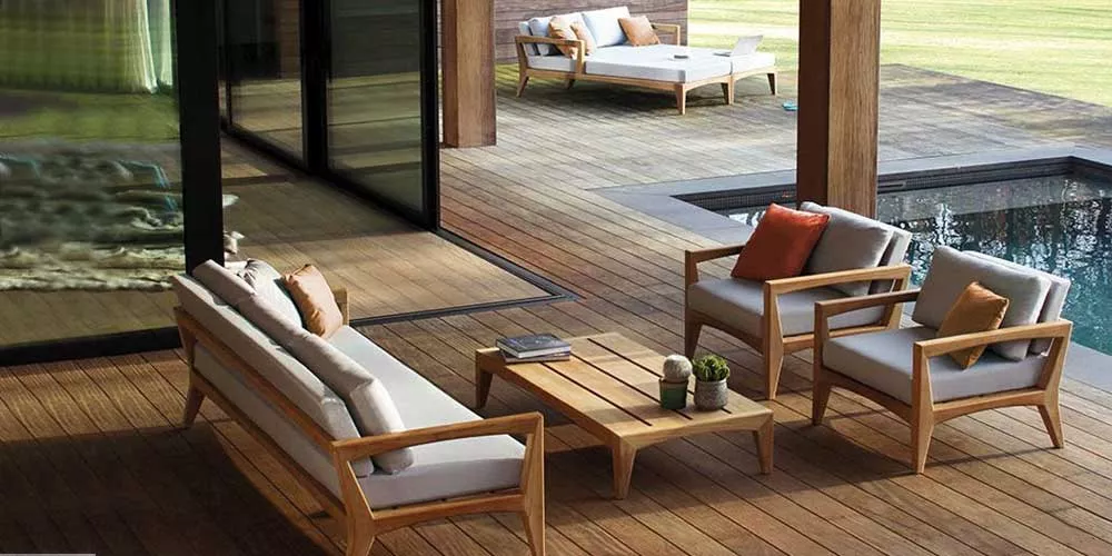 Royal Botania Zenhit Loungegruppe in Holzoptik auf einer Terrasse mit Pool im Hintergrund, gemütliche Gartenmöbel für entspannte Stunden.