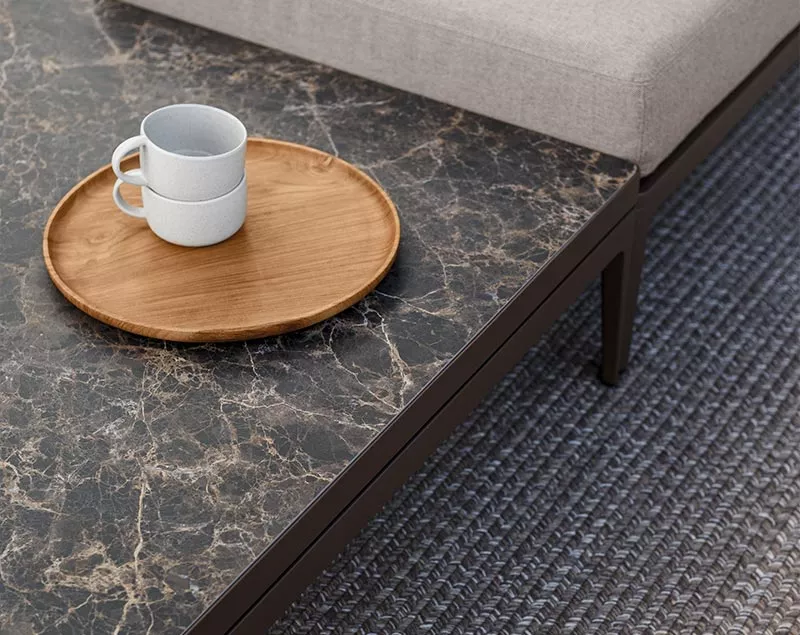 Ein Grid Tisch von Villa Schmidt in Marmoroptik mit einer Holzplatte und Tassen, auf einem geflochtenen Teppich, aus der Vogelperspektive.