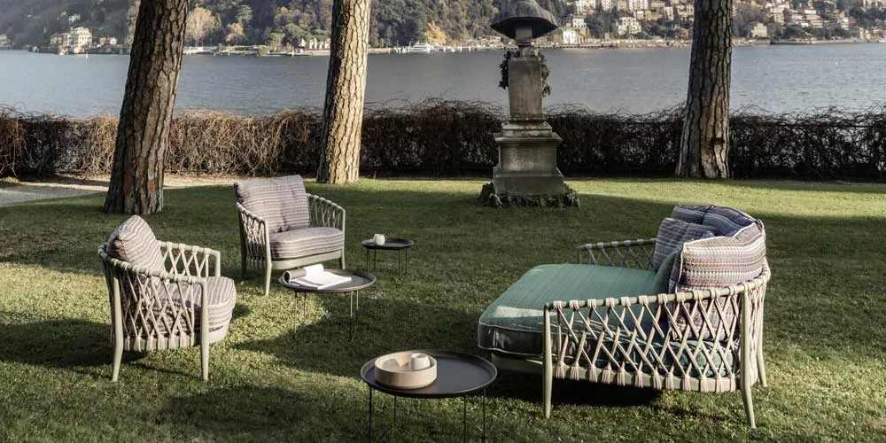 B&B Italia Erica 19 Outdoor Loungegruppe bestehend aus einem Loungesofa zwei Sesseln und zwei Beistelltischen in einem Garten am See.