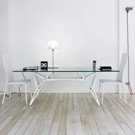 Moderner Reale Tisch von Villa Schmidt in Weiß mit Glasplatte, umgeben von zwei weißen Stühlen, auf hellem Holzboden in minimalistischem Raum.