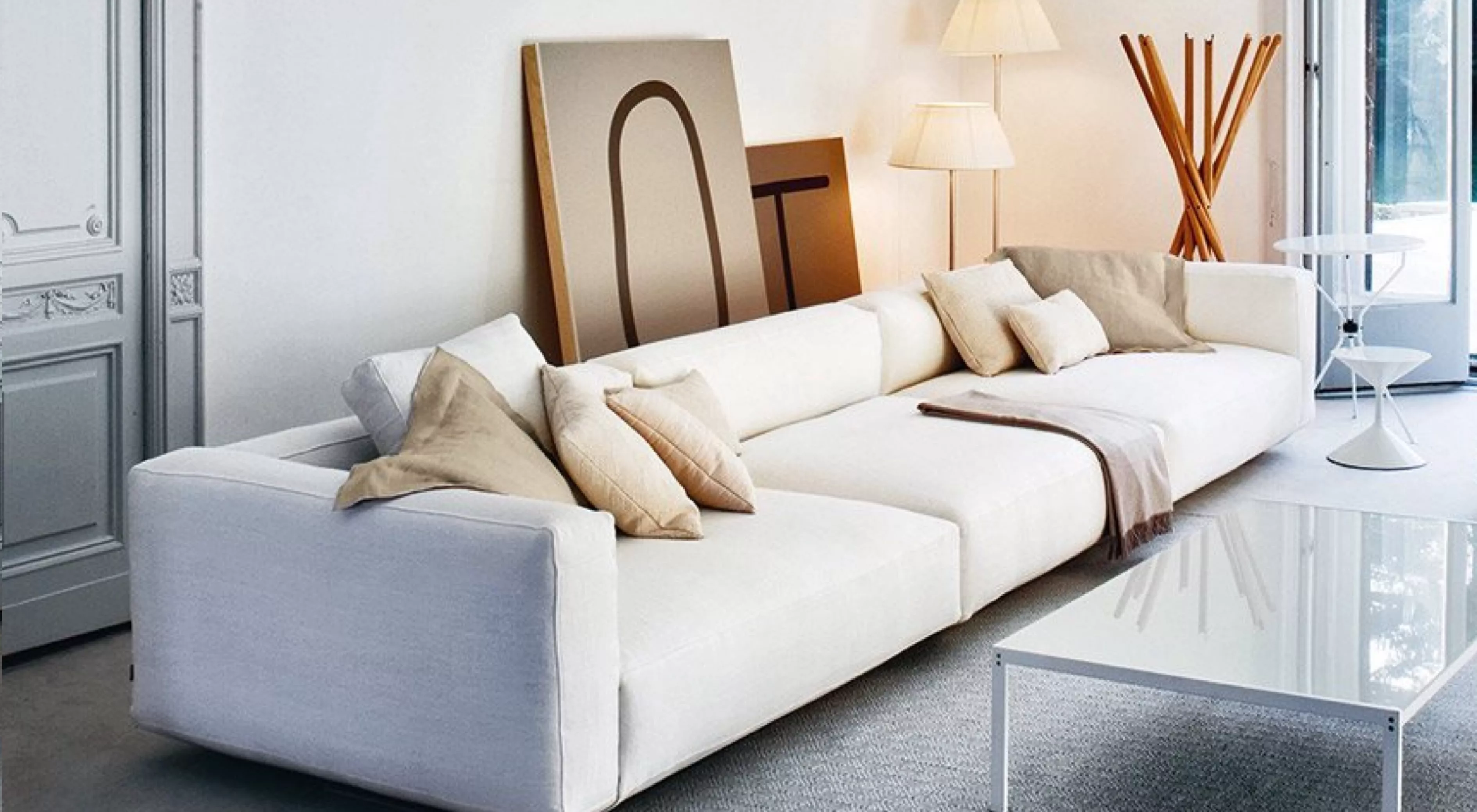 Ein elegantes, weißes PIANOALTO-Sofa in einem modernen Wohnzimmer mit Kunstwerken im Hintergrund und einem weißen Couchtisch im Vordergrund.