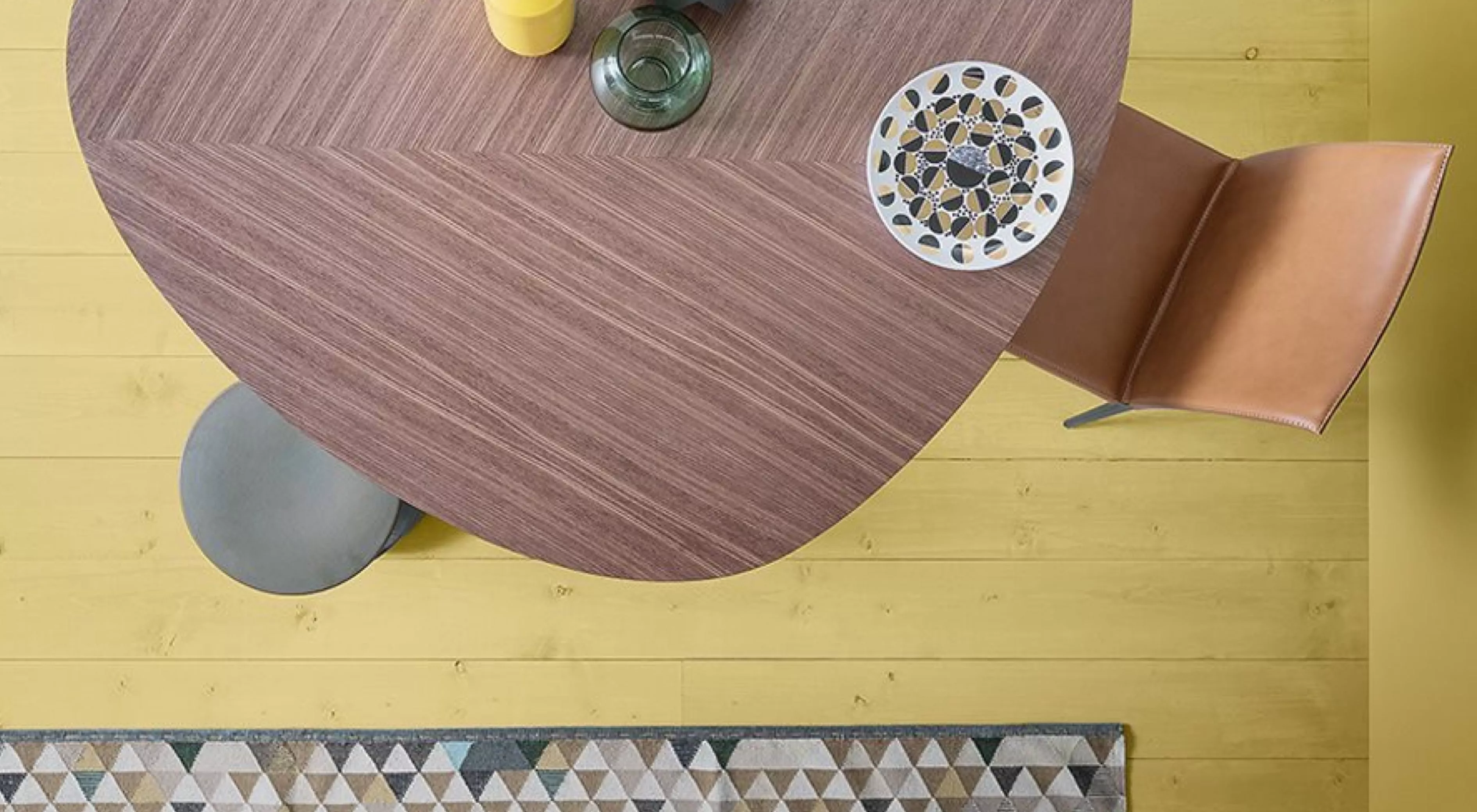 Der Zanotta Tweed Tisch in Holzoptik steht auf einem gelben Holzboden mit einem Stuhl und Dekorationen darauf Moodbild von oben.