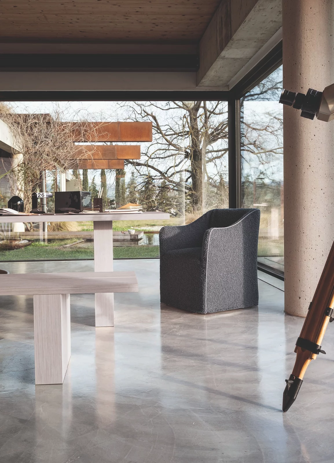 Ein Gervasoni Sessel steht in einem modernen Wohnzimmer mit großen Fenstern und Blick auf einen Garten im Hintergrund.