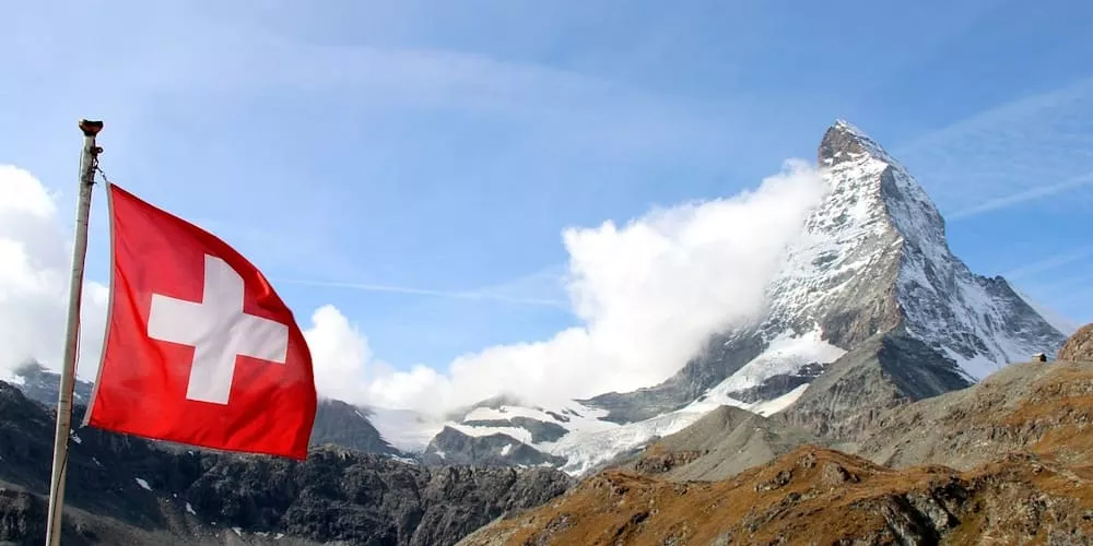 Schweizer Flagge weht vor dem Matterhorn bei klarem Himmel, stimmungsvolles Landschaftsbild.