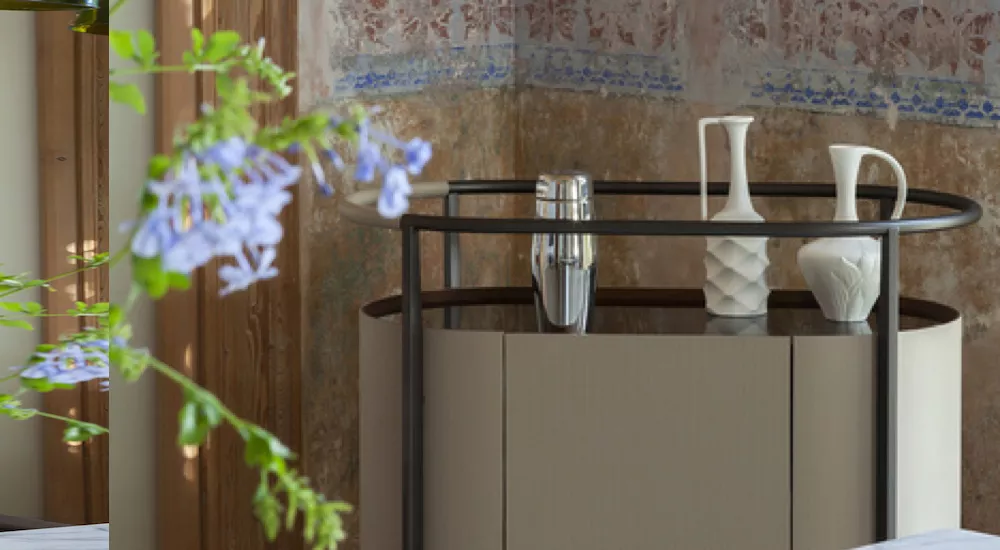 Poltrona Frau Mi Sideboard in Beige mit dekorativen Vasen, vor einer antik wirkenden Wand, stimmungsvolles Interieur.