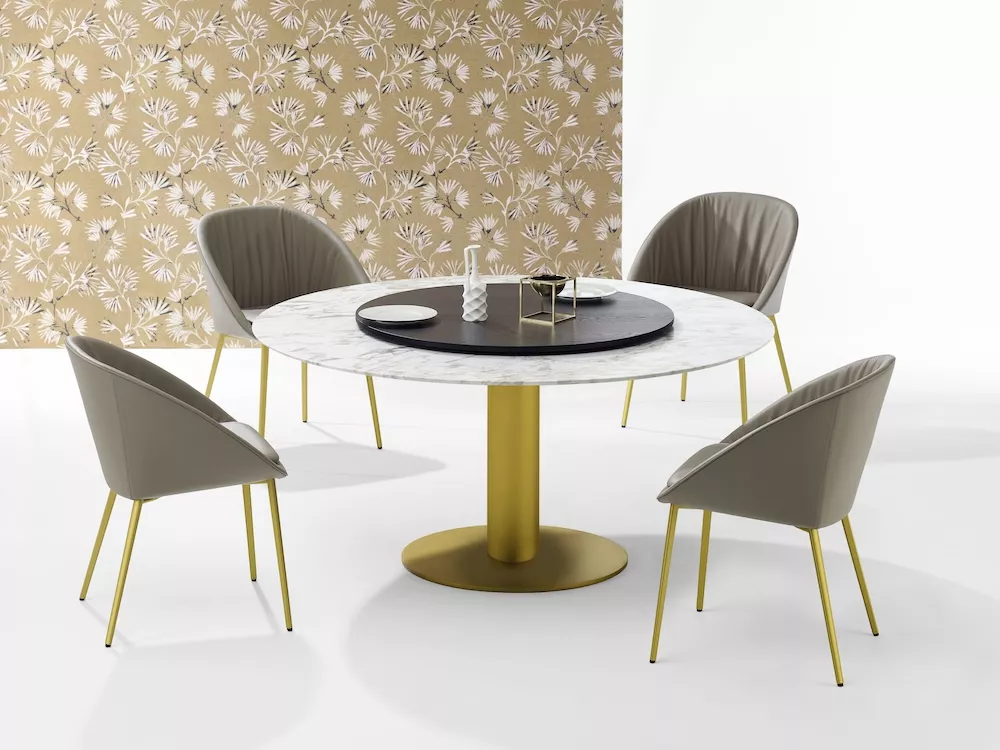 Draenert Nelly Esstisch mit rundem Marmortisch und vier grauen Stühlen mit goldenen Beinen vor einer gemusterten Tapete