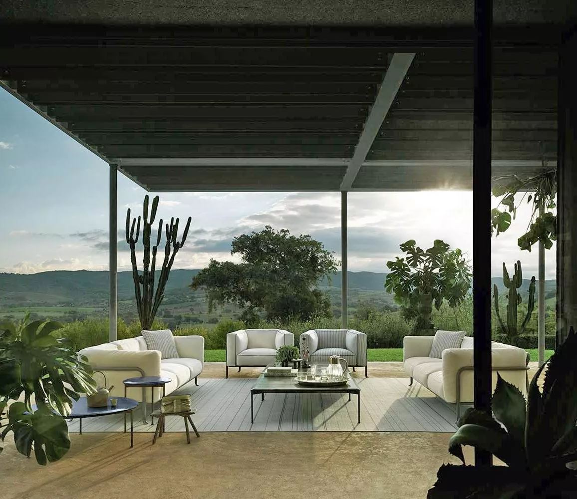 B&B Italia Borea Loungesofa und Outdoor Loungegruppe auf einer Terrasse mit Blick auf die Natur und umgeben von Pflanzen bei Sonnenuntergang.