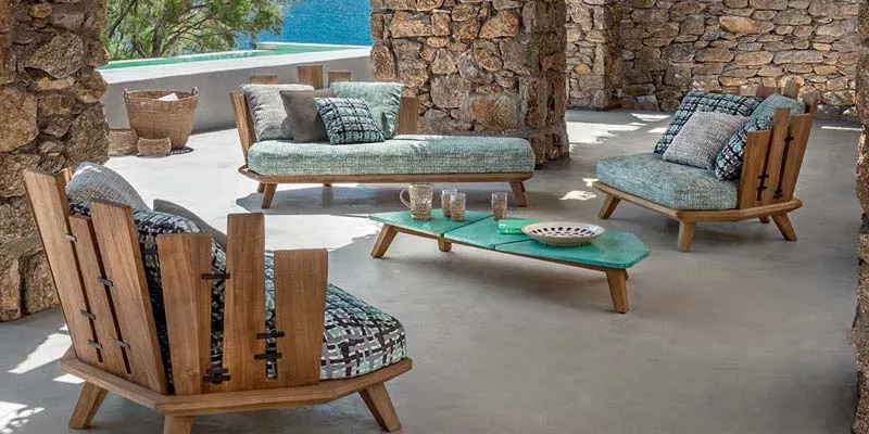 Ethimo Rafael Outdoor Loungegruppe in Natursteinumgebung mit türkisfarbenen Polstern und Holzelementen, stimmungsvolle Terrassenszene.