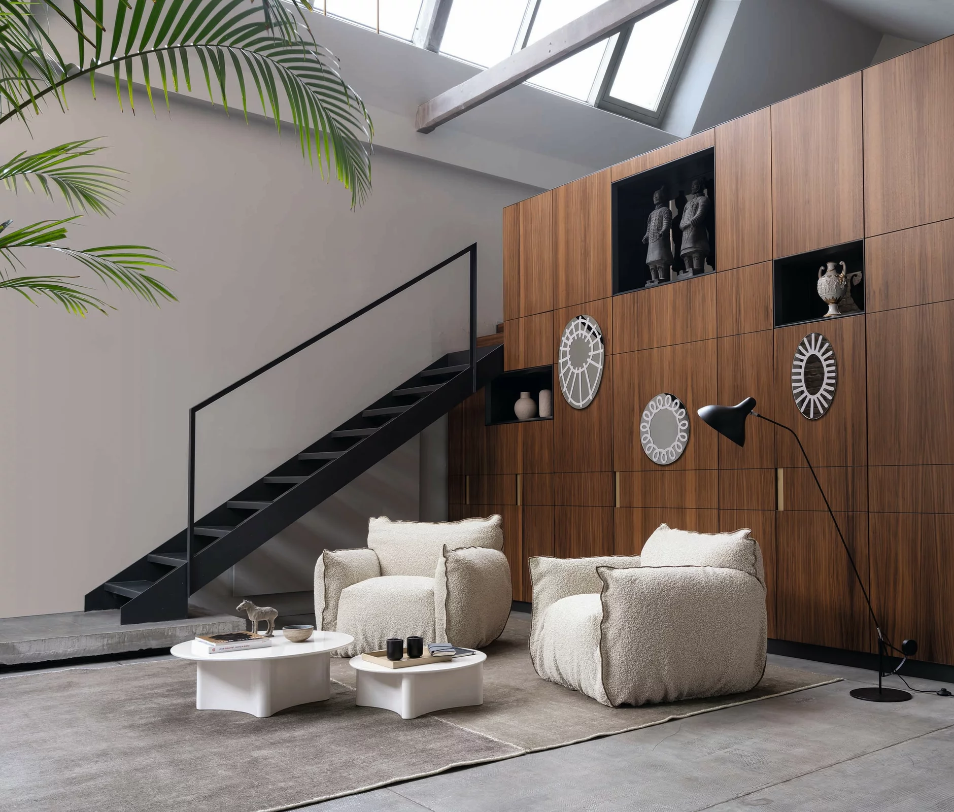 Zwei Gervasoni Inout 868 Sessel in einem modernen Wohnzimmer mit Holzwand Dekorationen und einer schwarzen Treppe im Hintergrund