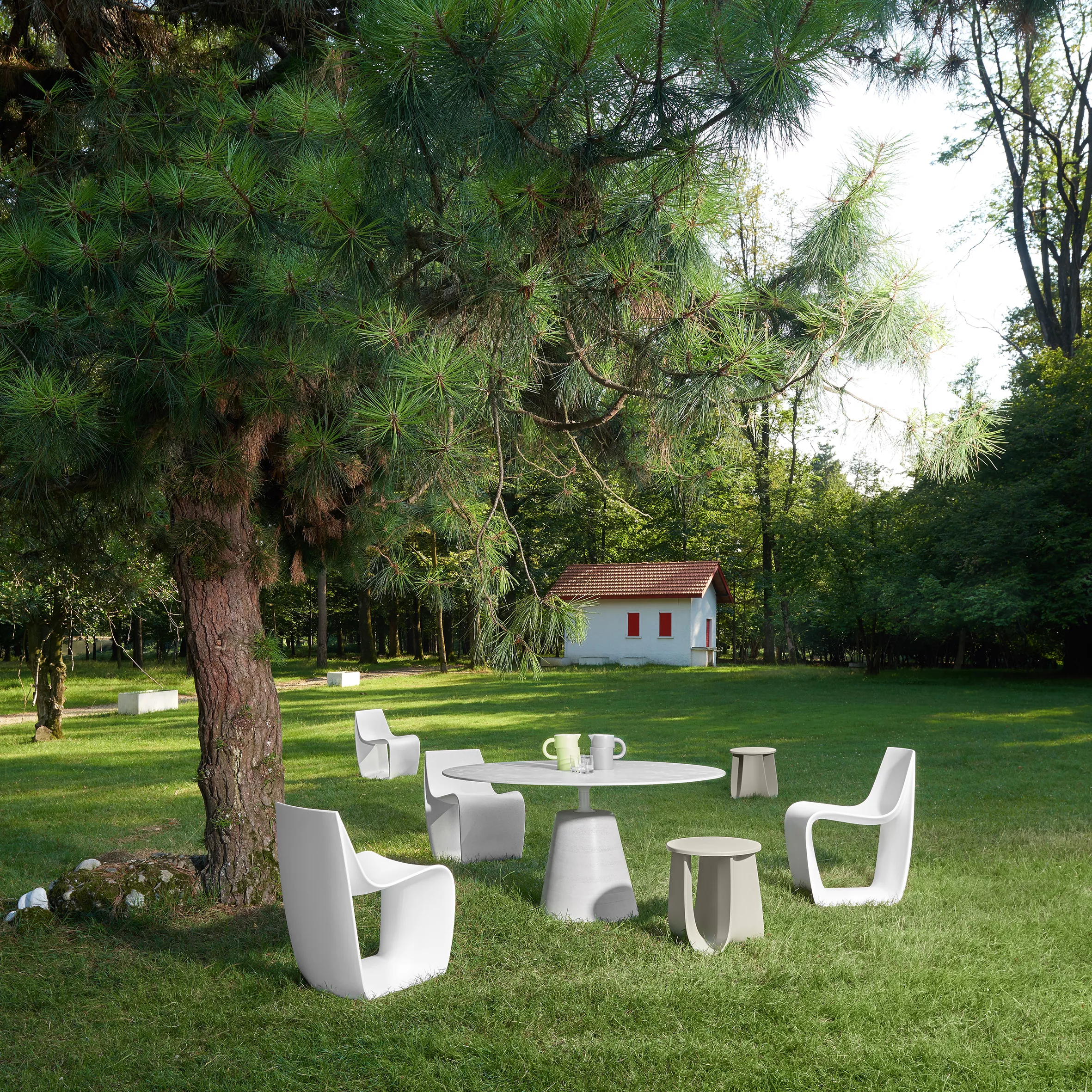 MDF Italia Sign Matt Stühle und Tisch stehen auf einer grünen Wiese unter einem Baum im Freien mit einem kleinen weißen Haus im Hintergrund.