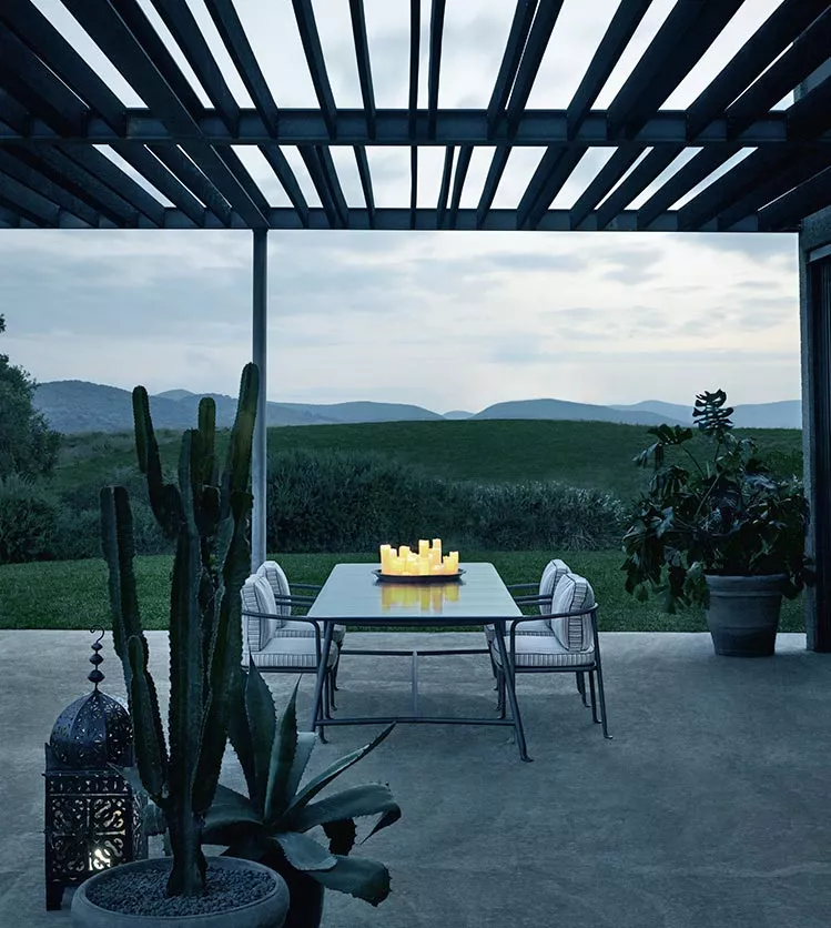 B&B Italia Borea Essgruppe auf einer Terrasse mit Blick auf eine grüne Landschaft und Berge im Hintergrund stimmungsvolles Bild bei Dämmerung.