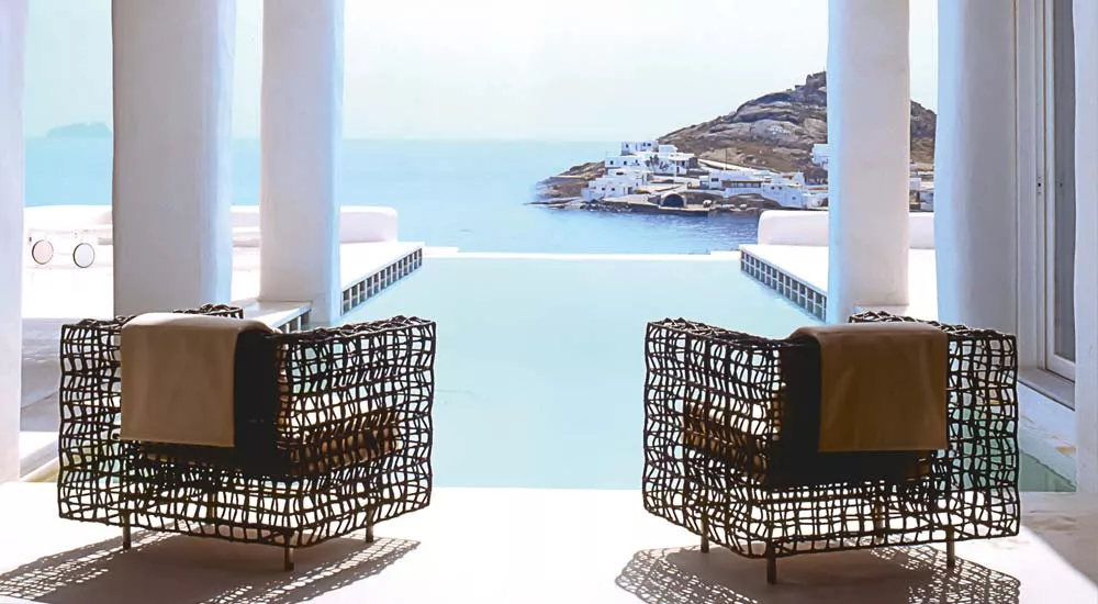 Zwei schwarze Kenneth Cobonpue Yin Yang Lounge-Sessel auf einer Terrasse mit Meerblick und weißem Hintergrund.