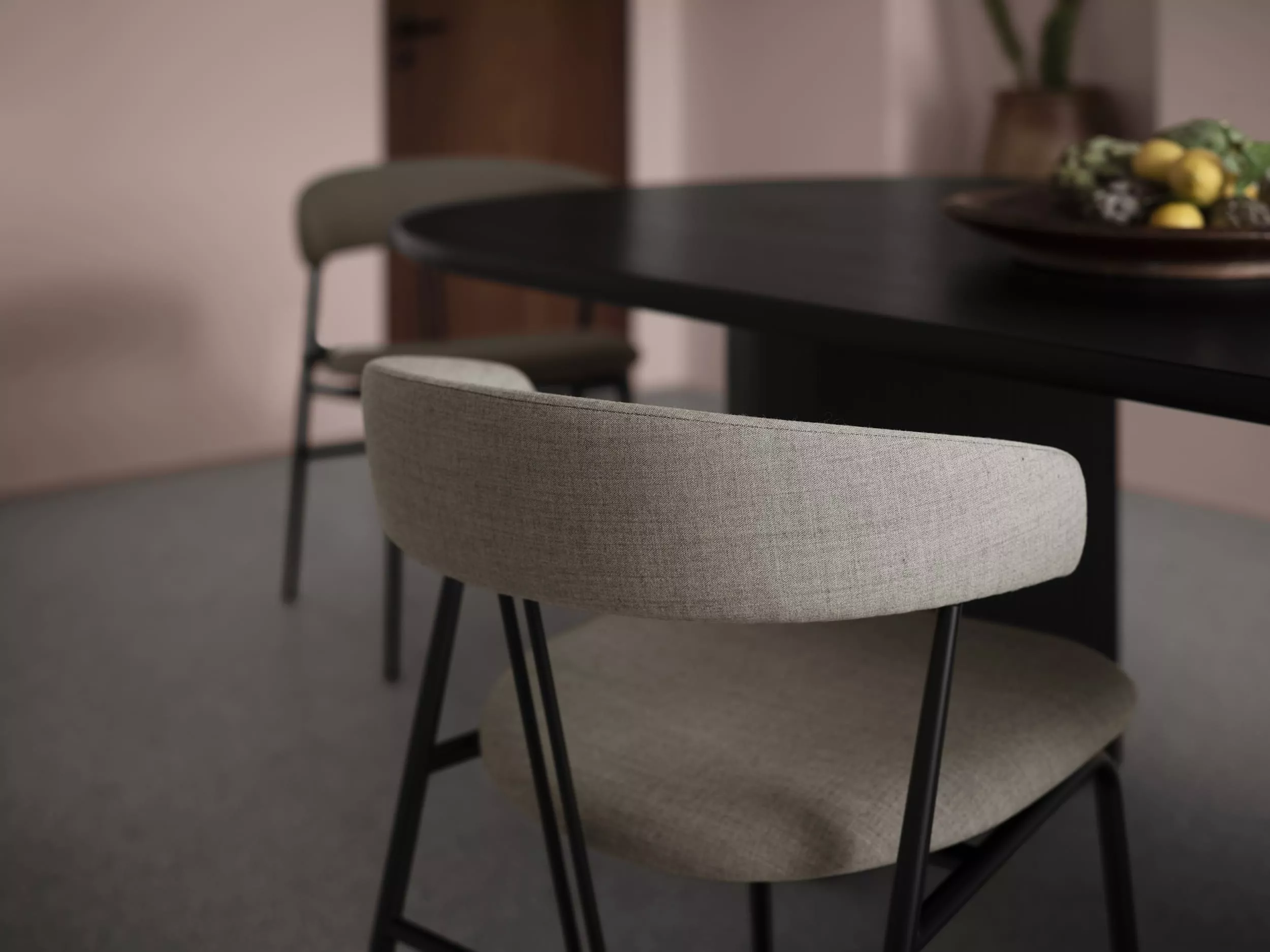 Zwei Gubi Violin Stühle in einem Esszimmer mit einem schwarzen Tisch und einer Schale mit Obst im Hintergrund