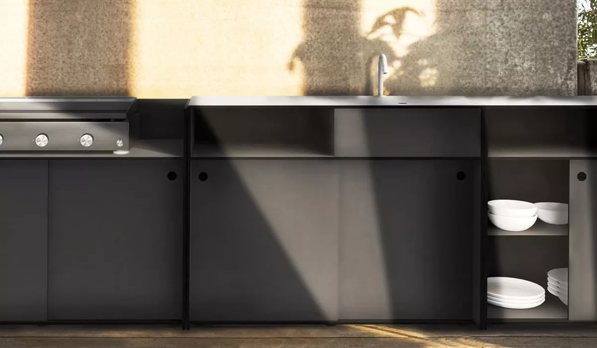 Conmoto Küche in Schwarz mit integriertem Grill und offenem Regal, stimmungsvolle Beleuchtung auf Betonhintergrund.