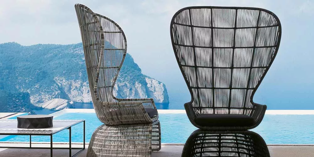 Zwei BeB Italia Crinoline Outdoor Loungesessel stehen auf einer Terrasse mit Blick auf das Meer und die Berge im Hintergrund