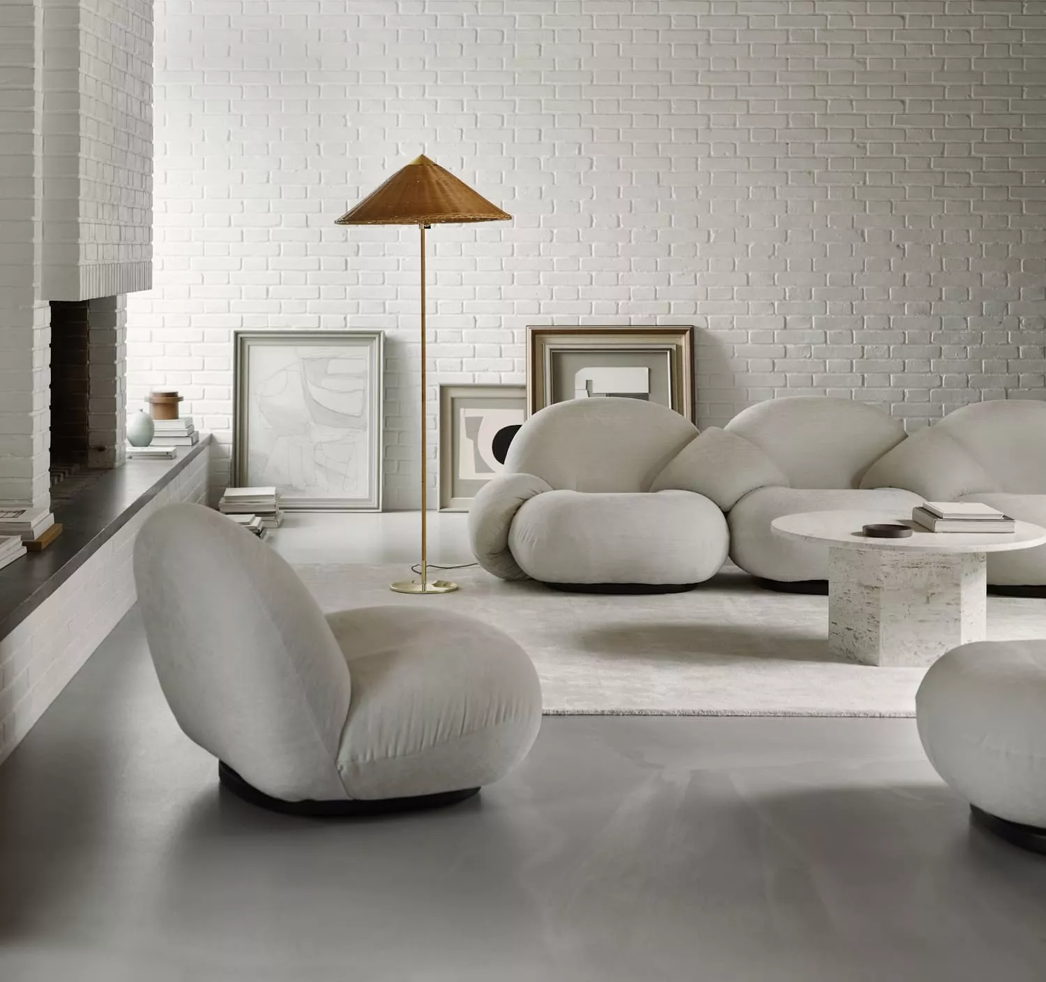 Gemütliches Wohnzimmer mit GUBI Pacha Lounge Chair in Weiß vor einer weißen Backsteinwand, umgeben von Kunstwerken und einem runden Tisch.