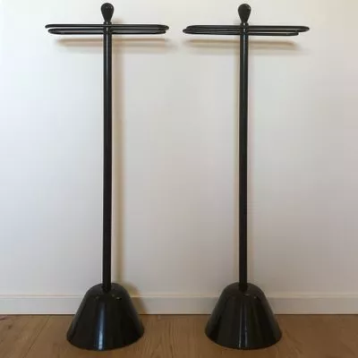 Zwei schwarze Servietto Handtuchhalter von Achille Castiglioni für Zanotta aus dem Jahr 1986 vor einer weißen Wand auf einem Holzboden.