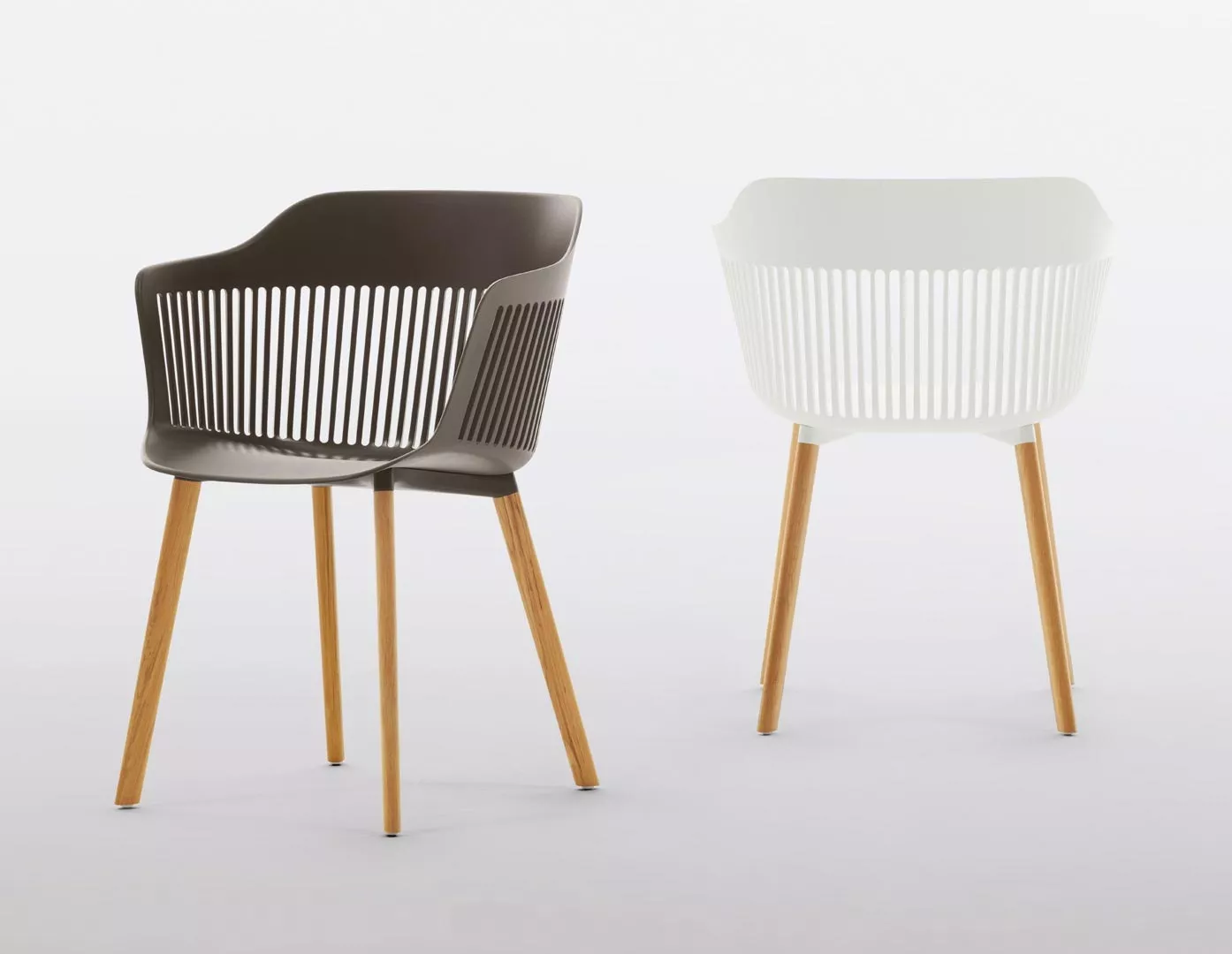 Dedon Aiir Armlehnstuhl in Braun und Weiß mit Holzbeinen auf grauem Hintergrund.