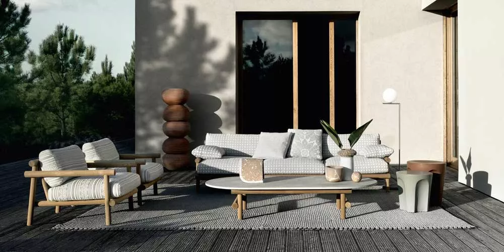 BeB Italia Ayana Loungegruppe mit Loungesofa und Sesseln auf einer Terrasse mit Holzboden und Pflanzen im Hintergrund in einer entspannten Atmosphäre